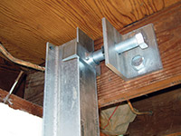 Securing the i-beam system to the top of the floor joist in a foundation wall repair in Vineland.