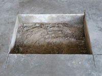 Creating the hole in the garage slab floor during the wall anchor installation in Kennett Square.