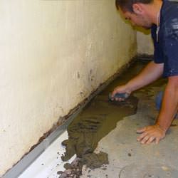 A basement waterproofer installing a perimeter drain system in Philadelphia