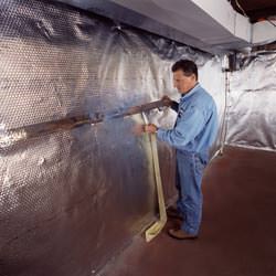 Installation of a radiant heat and vapor barrier on a basement wall in Camden