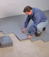 Contractors installing basement subfloor tiles and matting on a concrete basement floor in Wilmington, Pennsylvania, New Jersey, and Delaware